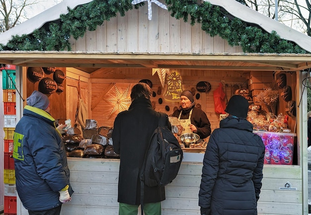 Vilnius, Lituânia - 4 de dezembro de 2016: Pessoas na barraca de Natal no mercado de Natal na Praça da Catedral, Vilnius.
