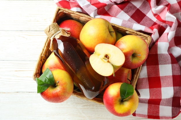 Vinagre de maçã caseiro e ingredientes na mesa de madeira branca