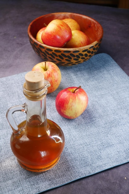 Vinagre de manzana en botella de vidrio con manzana verde fresca en la mesa