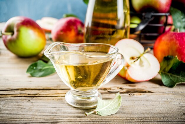 Vinagre de manzana casero con manzanas frescas om fondo rústico de madera