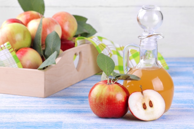 Vinagre de manzana con manzanas frescas maduras sobre un fondo de madera