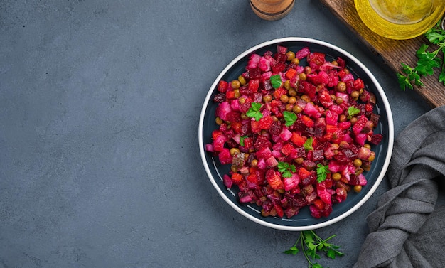 Vinagrete de salada tradicional com ervilhas vegetais de beterraba e ervas frescas em um fundo escuro