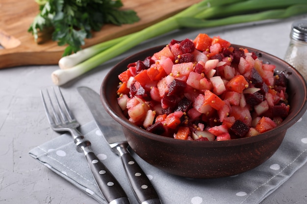 Foto vinagrete tradicional de salada russa com beterraba, cenoura, batata e cebola em uma tigela de barro