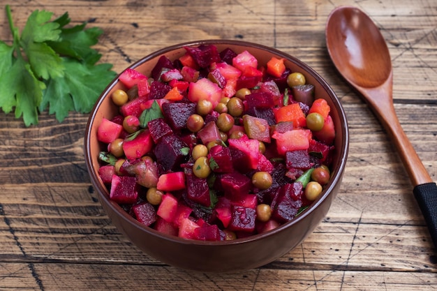 Vinaigrette mit roter Beete und gekochtem Gemüse, traditioneller russischer hausgemachter Salat. Hölzerner rustikaler Hintergrund, Kopienraum.