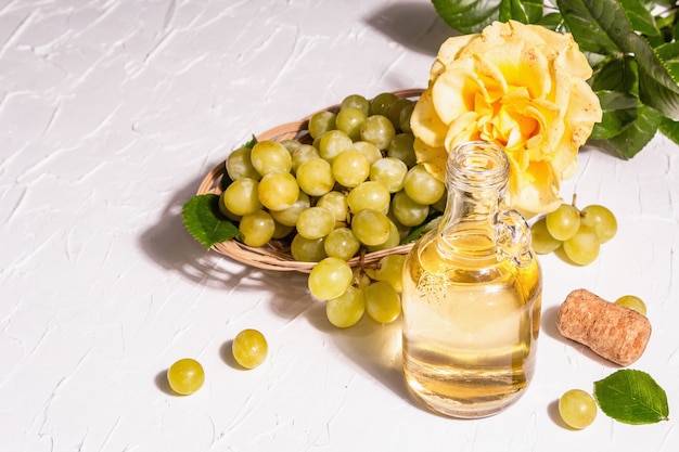 Vinho branco e uva em uma cesta de vime. Frutas frescas e flor rosa. Uma luz forte e moderna, sombra escura, espaço de cópia