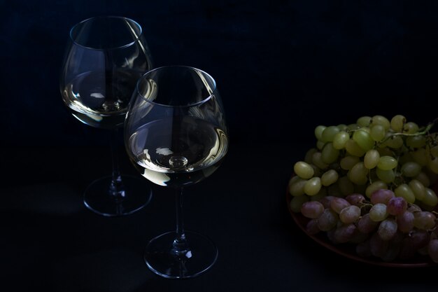 Vinho branco e uvas em uma superfície escura