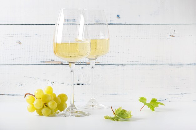 Vinho branco em um copo e um cacho de uvas