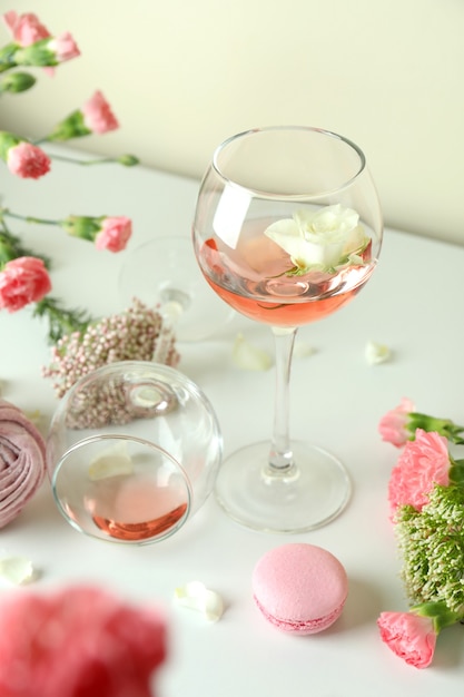 Vinho, comida doce e flores na mesa branca