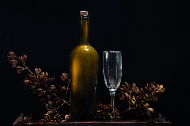 Foto vinho de garrafa de luxo e flores secas em fundo preto