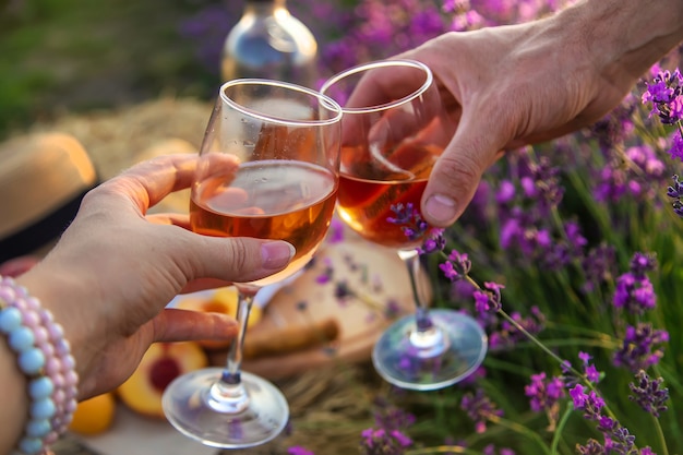 Vinho em taças é segurado por uma mulher e um homem em um campo de lavanda. Foco seletivo. Natureza.