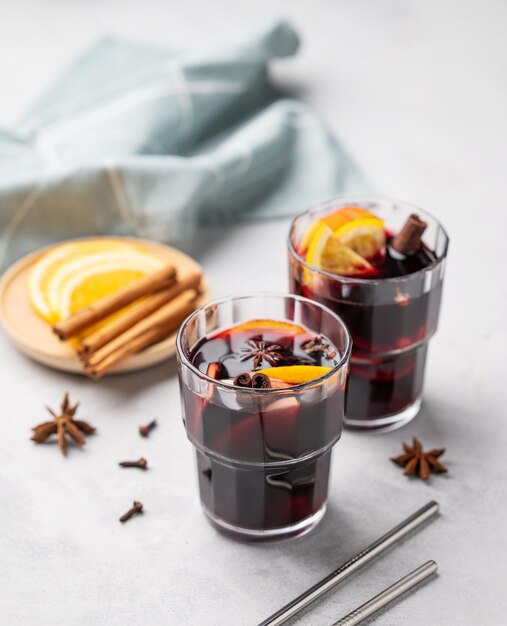 Vinho molled com maçã laranja e canela em copos em um fundo claro O conceito de uma bebida quente tradicional de inverno