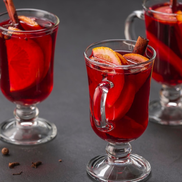 Vinho quente alcoólico com especiarias de frutas em uma bebida alcoólica tradicional de fundo escuro Natal