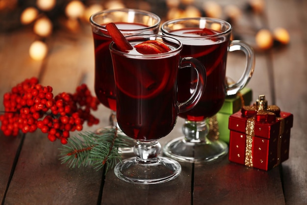 Vinho quente com especiarias e árvore de Natal com fundo de madeira