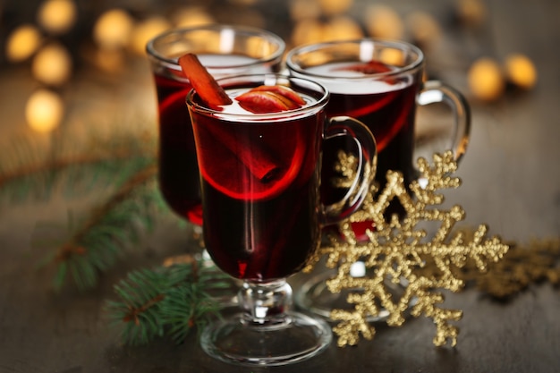 Vinho quente com especiarias e árvore de Natal na parede de madeira