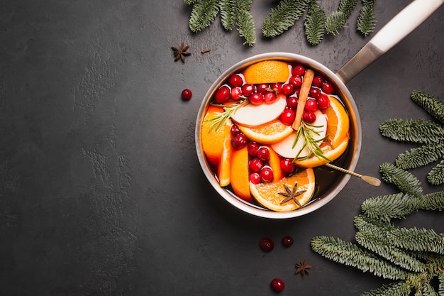 Vinho quente com frutas, alecrim na mesa de pedra preta