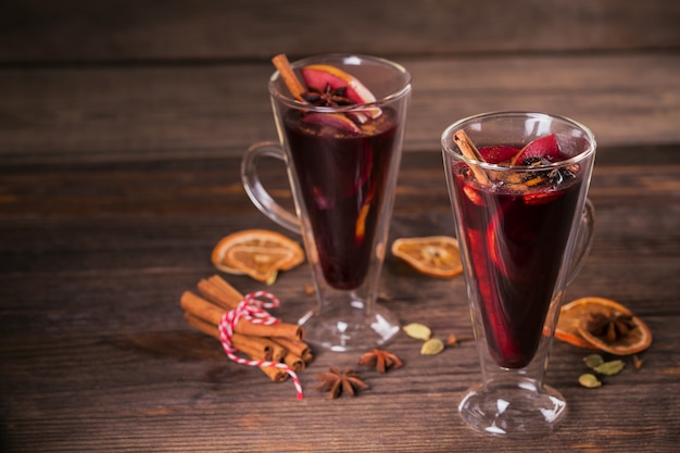 Vinho quente com frutas, paus de canela e anis em fundo escuro de madeira. Bebida de aquecimento do inverno com ingredientes da receita.