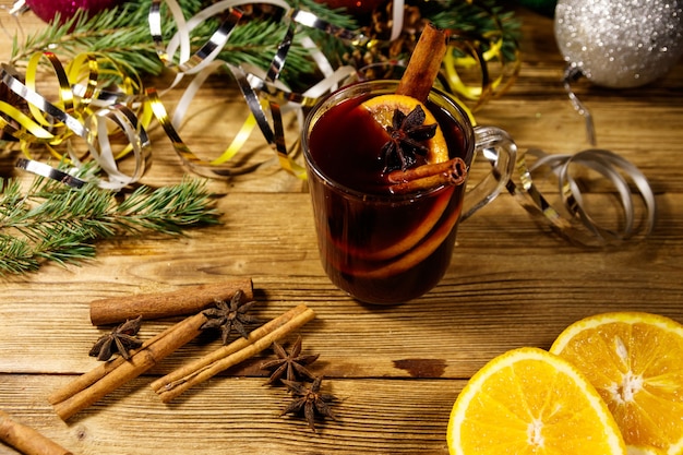 Vinho quente de natal com especiarias e decoração de natal na mesa de madeira