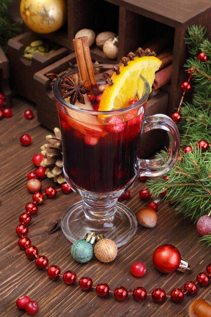Vinho quente de Natal com maçã, cranberry, laranja, especiarias e chocolate em uma mesa de madeira