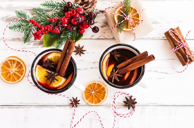 Vinho quente em canecas, frutas secas e especiarias na mesa wite, vista superior.