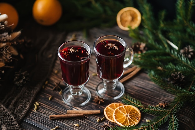 Vinho quente em copos com fatias de laranja, canela, cravo