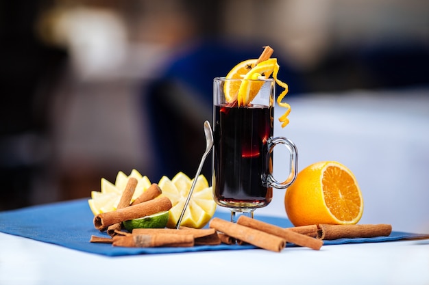 Vinho quente em uma caneca de vidro com laranja e canela