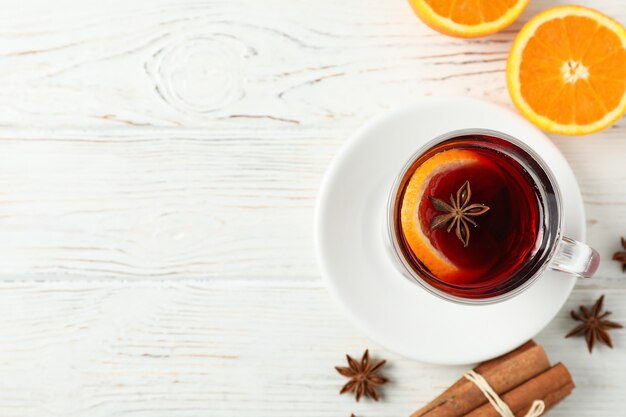 Vinho quente, laranja e canela na mesa de madeira branca, vista superior