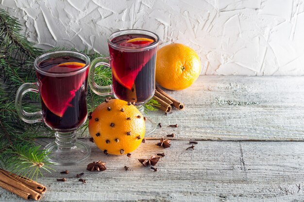 Vinho quente quente de Natal com canela laranja e anis em fundo branco de madeira