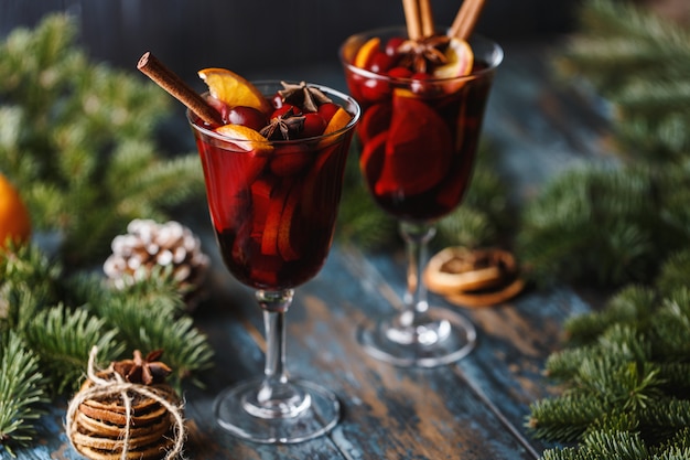 Vinho quente quente de Natal em um copo com especiarias, frutas cítricas e amora. Atmosfera de Natal.