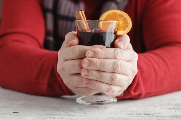 Vinho quente quente nas mãos masculinas, especiarias na mesa de madeira resistida. conceito de lar doce