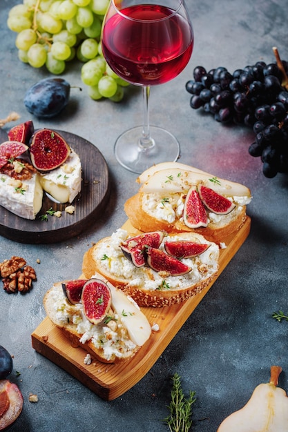 Vinho tinto com petiscos bruschetta com peras requeijão figos tomilho nozes e mel camembert queijo