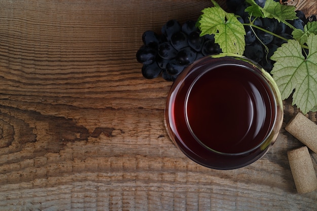 Vinho tinto e uvas. vinho e uvas em um ambiente vintage com rolhas em uma mesa de madeira. vista do topo.