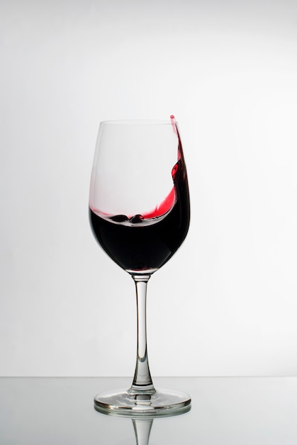 Foto vinho tinto, espirrando o lado de um copo de vinho