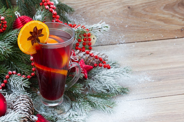 Foto vinho tinto quente com árvore de natal decorada na neve em fundo de madeira