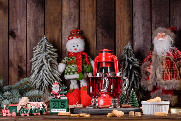 Vinho tinto quente com especiarias e frutas de Natal em uma mesa escura. Bebida quente tradicional na época do Natal