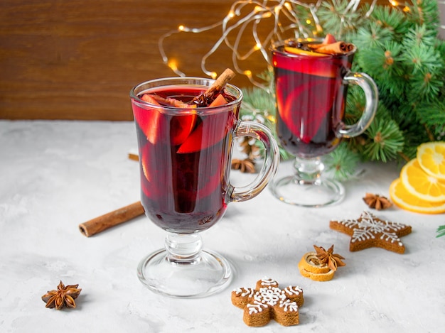 Foto vinho tinto quente com especiarias e laranjas de natal em uma mesa de madeira rústica. bebidas tradicionais de ano novo.