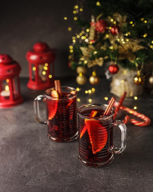 Foto vinho tinto quente com especiarias em duas xícaras de vidro para o inverno e natal com maçã laranja e especiarias diversas