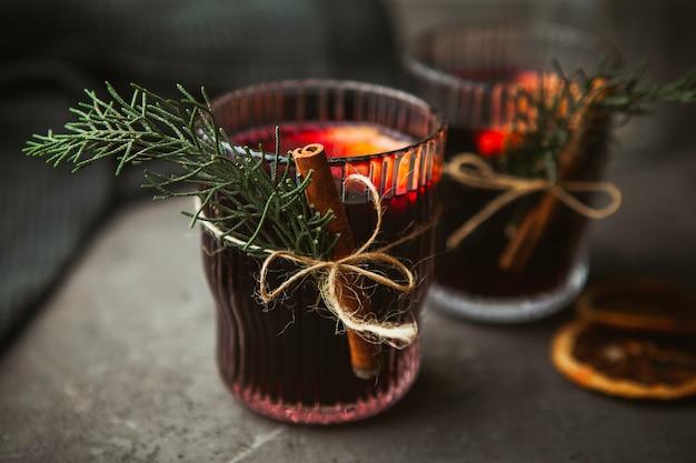 Vinho tinto quente de Natal com especiarias aromáticas e frutas cítricas na superfície preta, close-up. Bebida quente tradicional na época do Natal