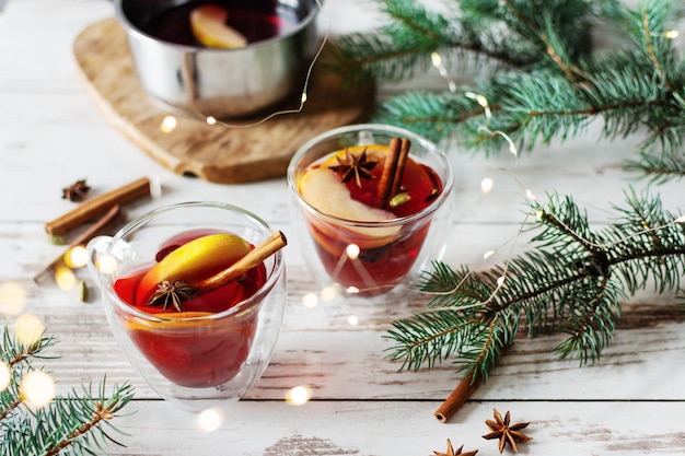 Vinho tinto quente de natal com especiarias e frutas sobre fundo decorado de natal