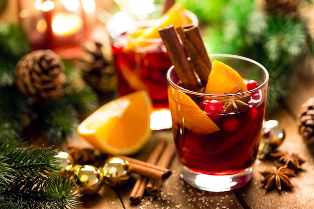Vinho tinto quente de Natal com especiarias e laranjas numa mesa rústica de madeira Bebida quente tradicional no Natal
