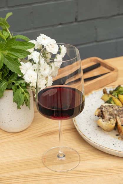 Vinho vermelho em copo de vinho na mesa com carne assada em massa em fundo de parede de tijolos