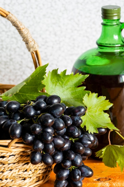 Vinificação em casa Uma enorme escova de uvas escuras frescas e suculentas no contexto de uma garrafa de vinho