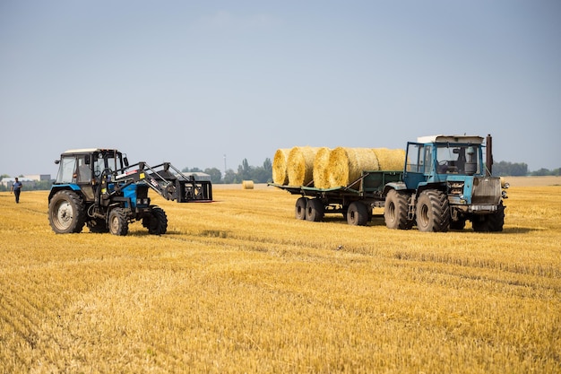 VinnitsaUcrania 26 de julio de 2016enorme tractor recogiendo pajar en el campo en un agradable día soleado azulTractor recogiendo fardos de pajaMáquina agrícola recogiendo fardos de cosecha de heno concepto