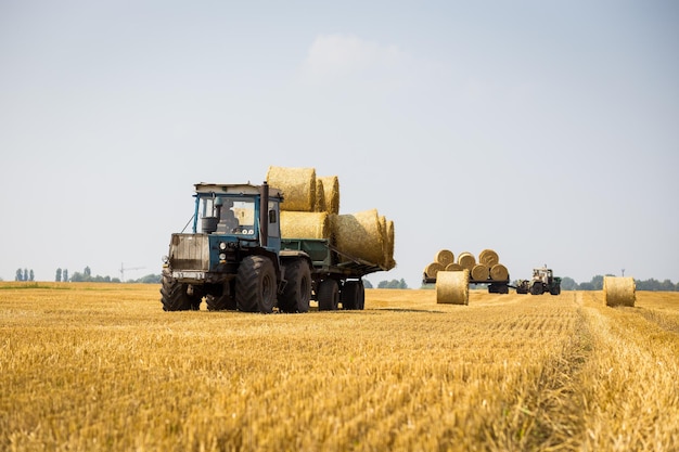 VinnitsaUcrania 26 de julio de 2016enorme tractor recogiendo pajar en el campo en un agradable día soleado azulTractor recogiendo fardos de pajaMáquina agrícola recogiendo fardos de cosecha de heno concepto