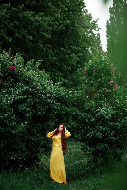 Vinnytsia Ucrânia 15 de maio de 2021 Uma linda jovem de vestido amarelo longo com cabelo comprido fica em um parque verde