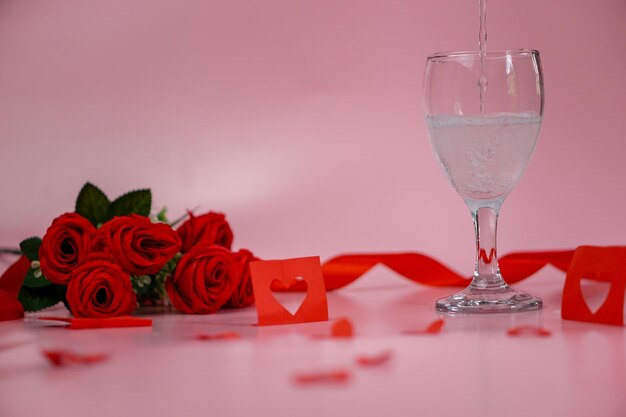 Vino blanco y rosas con cintas rojas y rosas en un fondo del Día de San Valentín