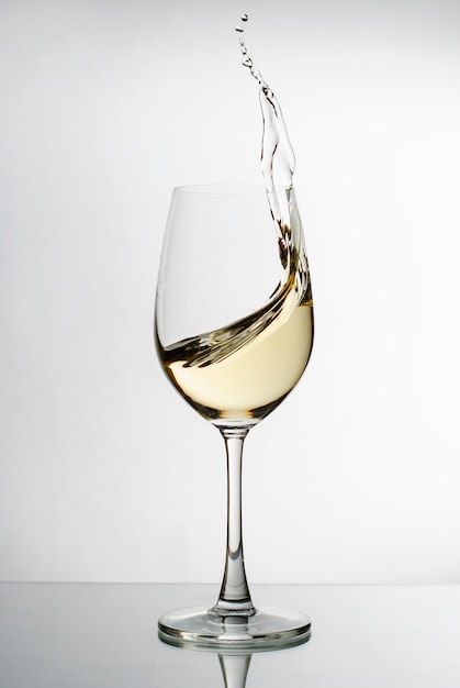 Foto vino blanco salpicado de una elegante copa de vino