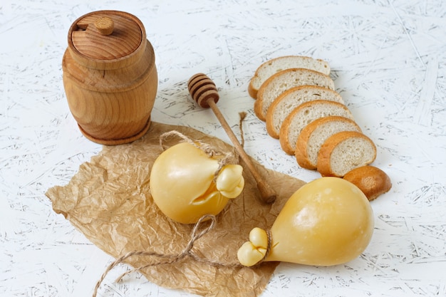Foto vino de caciocavallo del queso, miel, pan en un fondo blanco. pera de queso