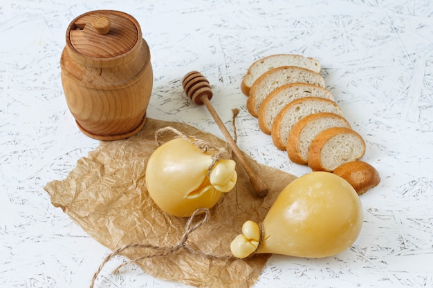 Vino de Caciocavallo del queso, miel, pan en un fondo blanco. Pera de queso