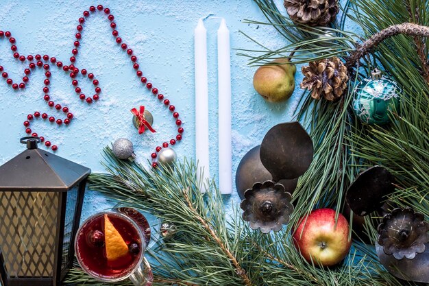 Vino caliente caliente con anís naranja, cardamomo y canela sobre fondo azul Ramas de árboles de Navidad regalos y conos