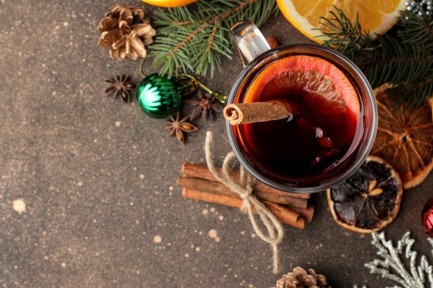 Vino caliente caliente con canela y naranja en vasos de vidrio y adornos navideños sobre un fondo oscuro. Vista desde arriba. Navidad. Año nuevo.